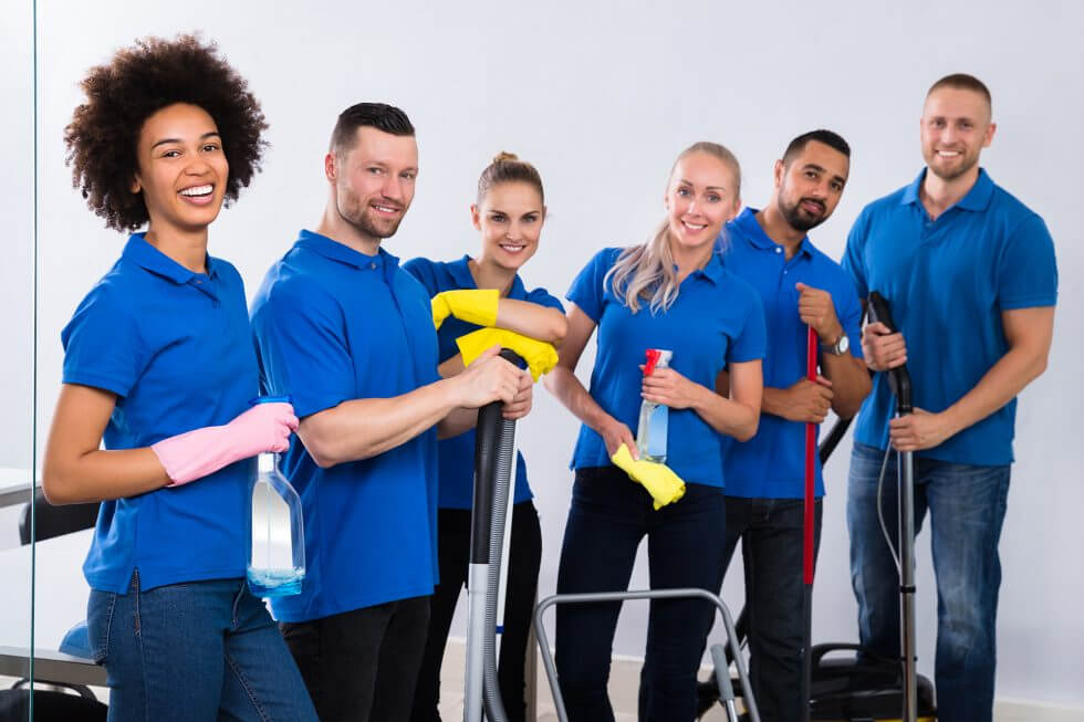 six people dressed in blue polos holding cleaning materials