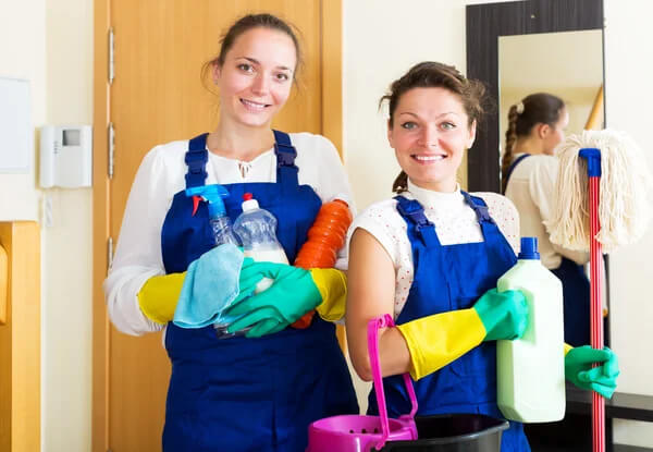 two women in blue overalls and yellow gloves
