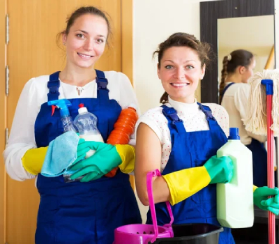 two women dressed in blue polos holding cleaning supplies